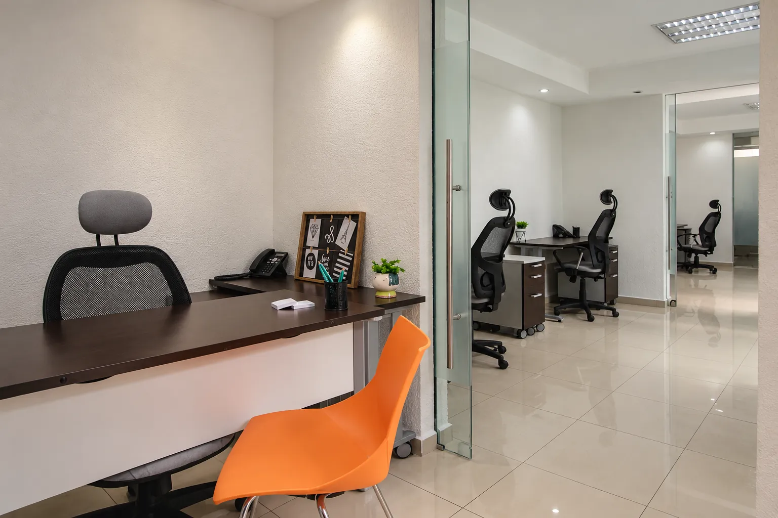 Oficina con escritorio oscuro, silla naranja y puertas de cristal, OfiRent Condesa, Ciudad de México