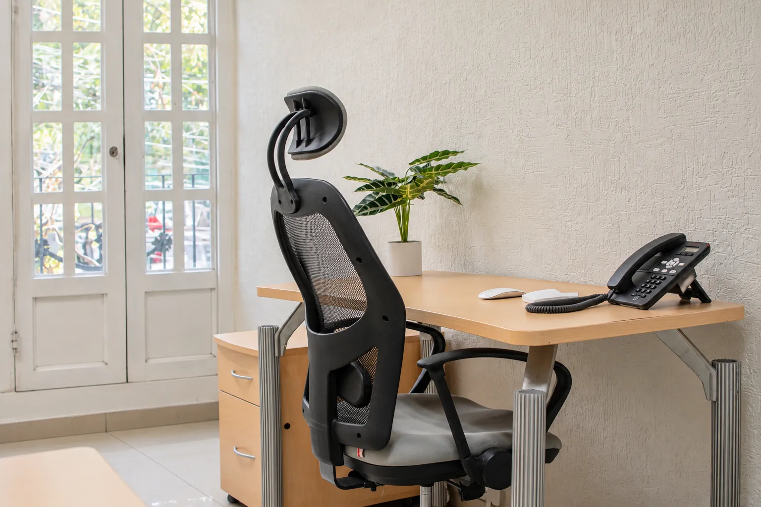 Escritorio con silla ergonómica y teléfono junto a puertas ventana, OfiRent Condesa, Ciudad de México