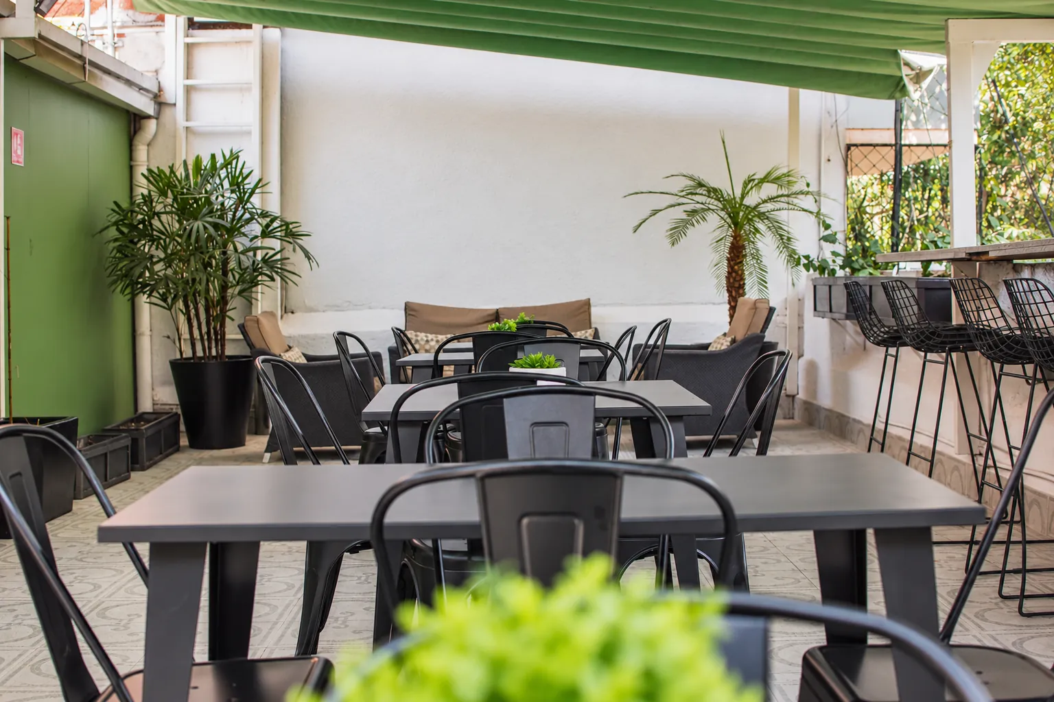 Terraza con mesas, bancos altos y plantas, OfiRent Condesa, Ciudad de México