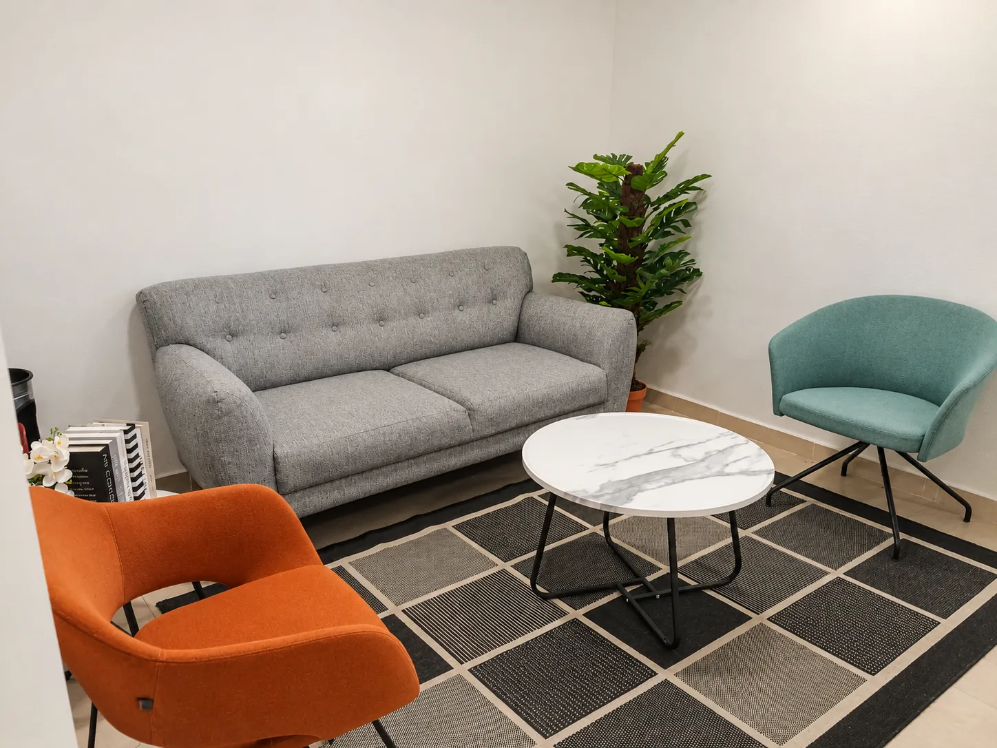 Sala de espera con sofá gris, sillones turquesa y naranja y mesa de mármol, OfiRent Del Valle, Ciudad de México