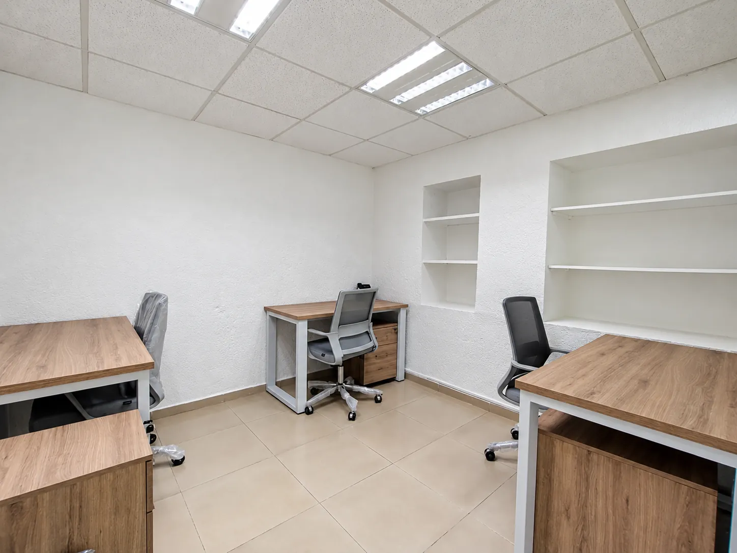 Oficina con escritorios de madera, silla de malla y repisas en la pared, OfiRent Del Valle, Ciudad de México