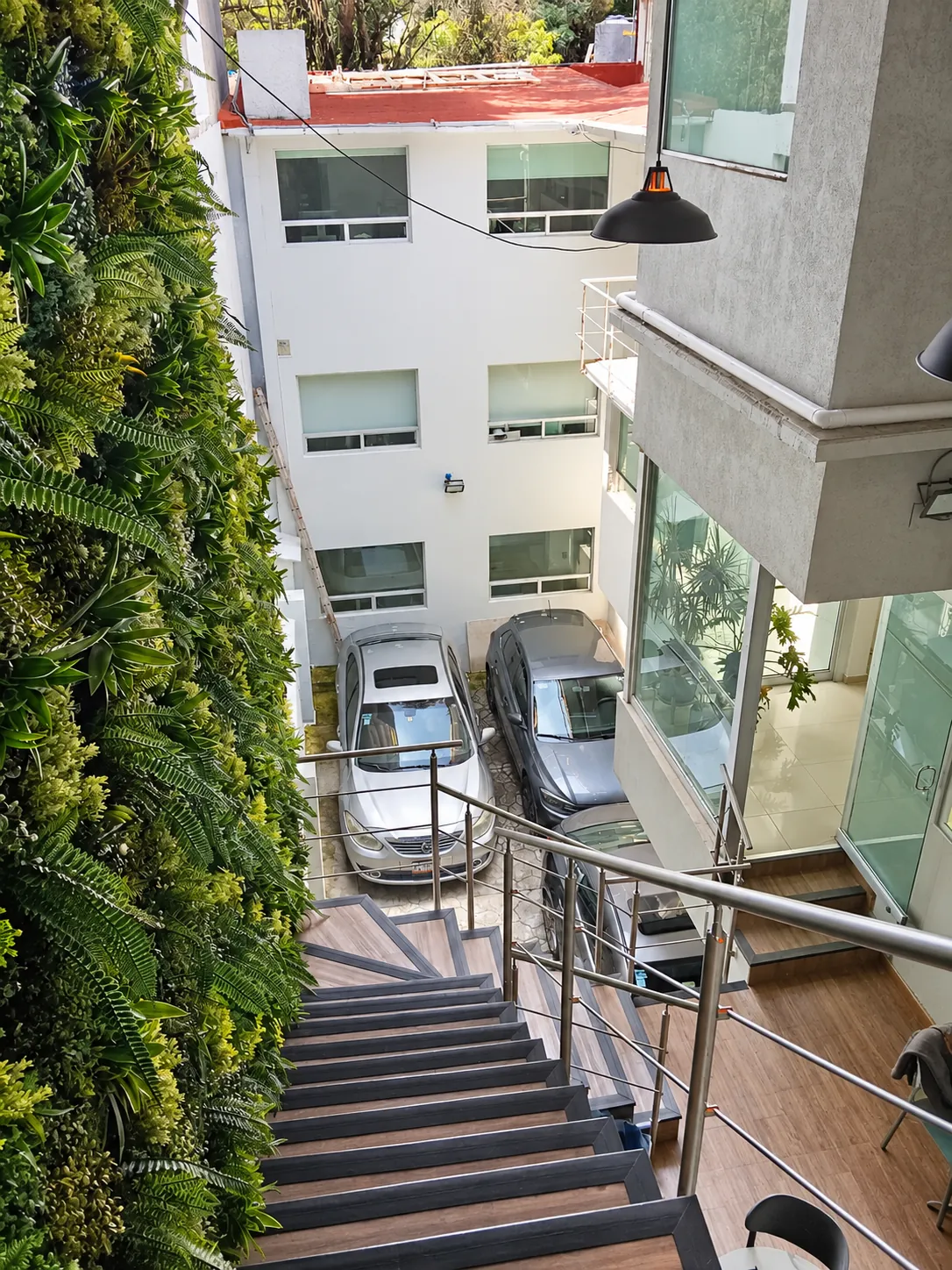 Escalera junto a un muro de plantas con vista al patio, OfiRent Del Valle, Ciudad de México