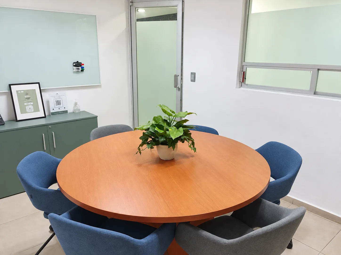 Sala de reuniones con mesa redonda, planta y pizarrón de vidrio, OfiRent Del Valle, Ciudad de México