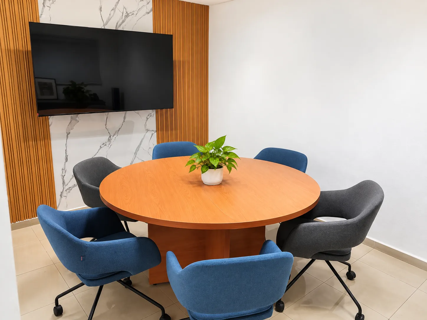 Sala de reuniones con mesa redonda, sillas azules y grises y pantalla en la pared, OfiRent Del Valle, Ciudad de México