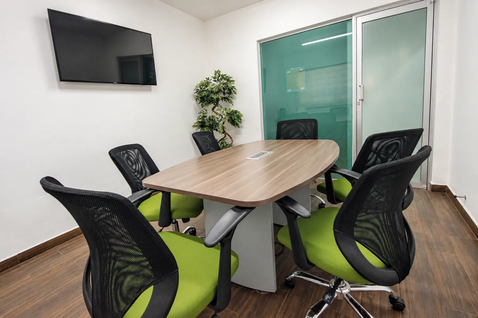 Sala de juntas con mesa ovalada, sillas verdes y pantalla, OfiRent Nápoles, Ciudad de México