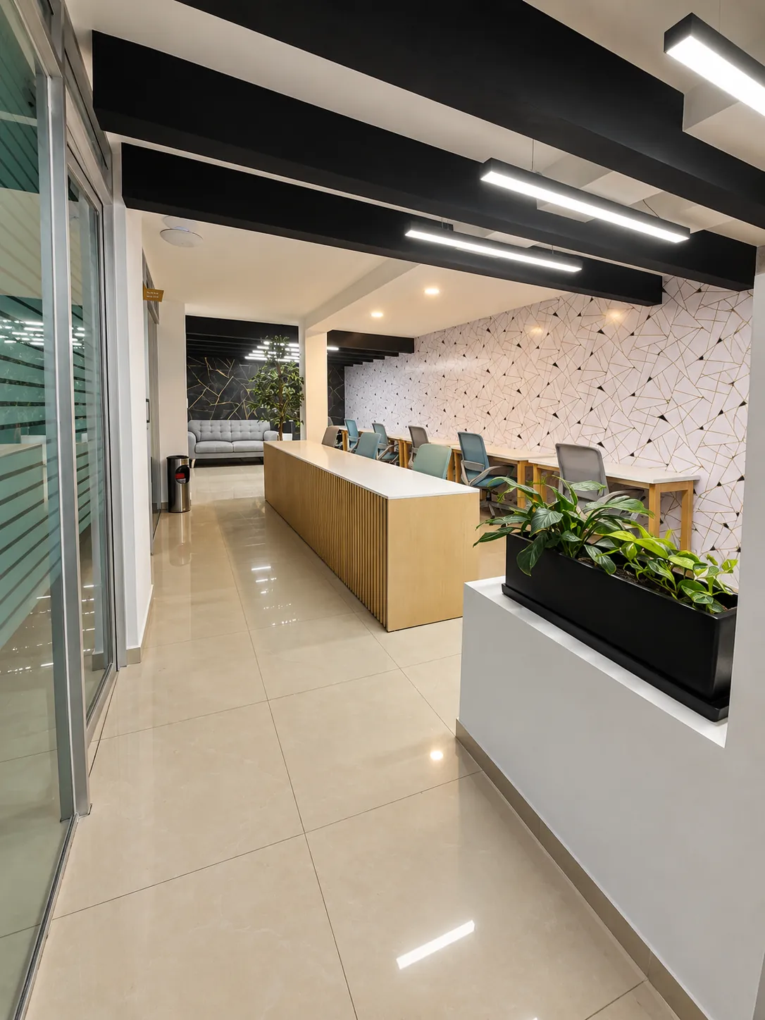 Zona de coworking con barra de trabajo, luces lineales y jardinera con plantas, OfiRent Narvarte, Ciudad de México