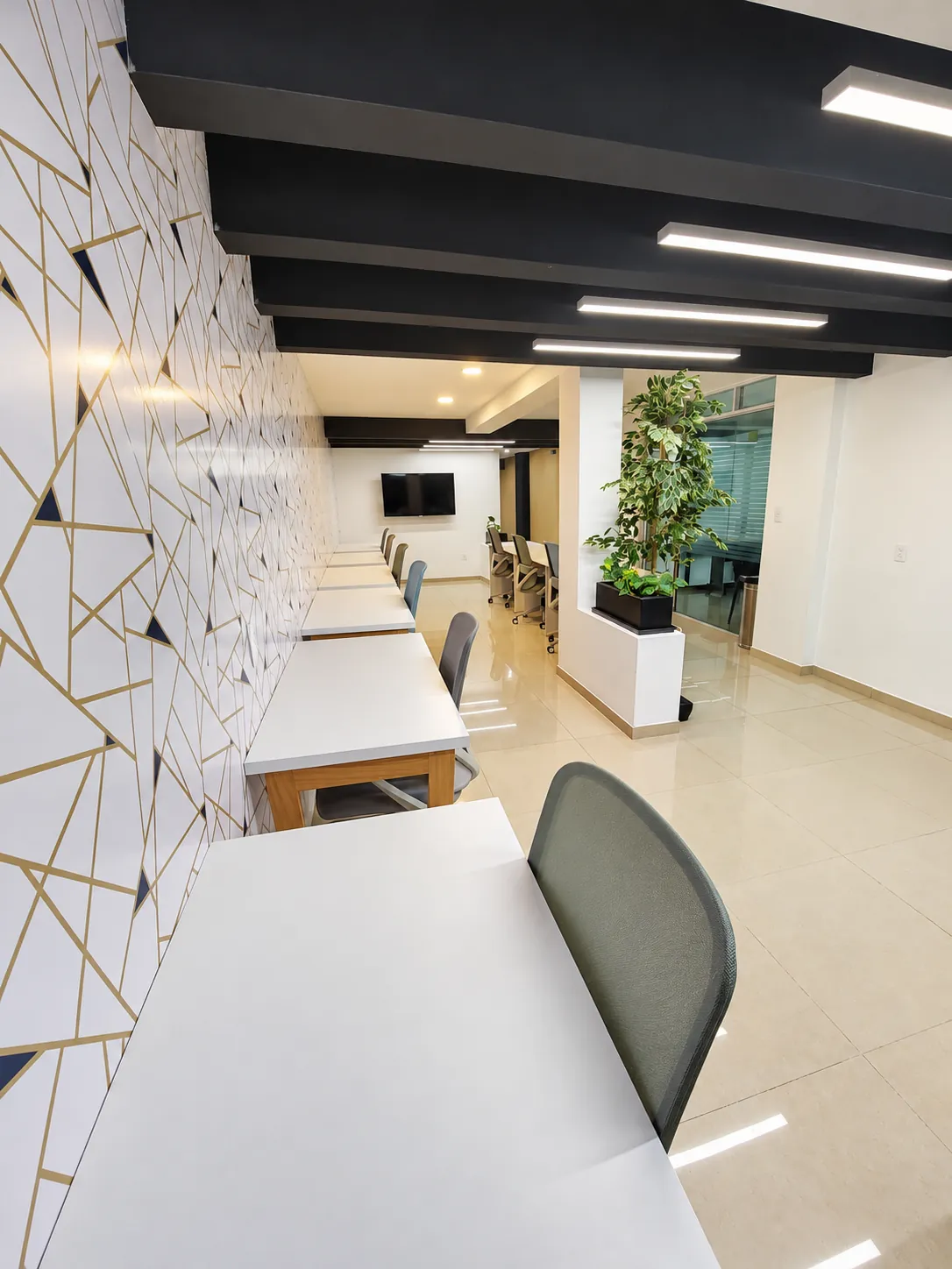 Área de coworking con mesa de trabajo blanca, sillas y pared decorativa, OfiRent Narvarte, Ciudad de México