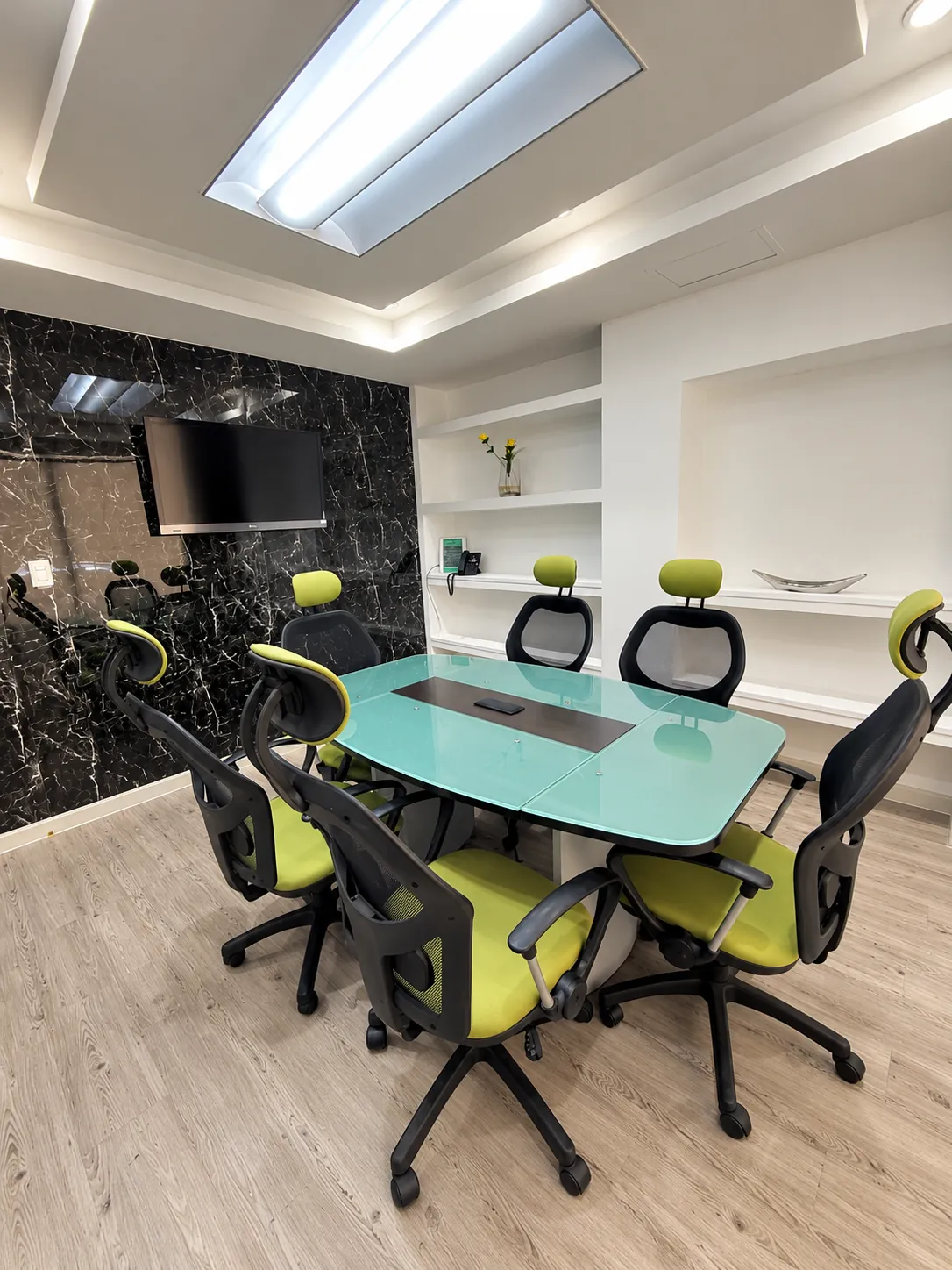Sala de juntas con mesa de cristal, sillas verdes y tragaluz, OfiRent Roma, Ciudad de México