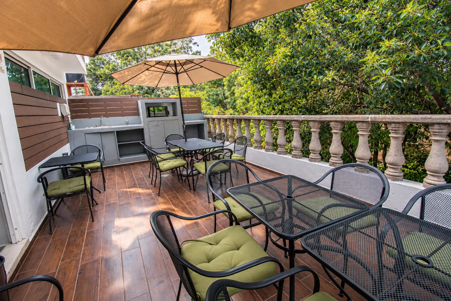 Terraza con sombrilla, mesas y sillas junto al barandal, OfiRent Roma, Ciudad de México