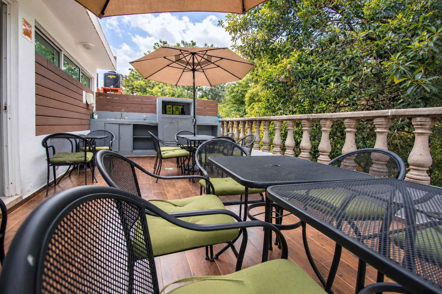 Terraza con sombrilla y mesas rodeada de árboles, OfiRent Roma, Ciudad de México